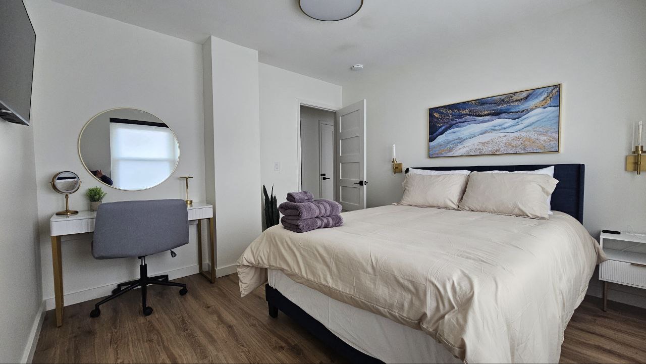 The Gatsby Room queen bedroom with gold accents, vanity desk, and designer art at Mojo Manor